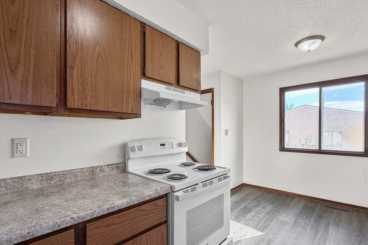 A townhome kitchen with oak cabinets, a white range and a window over the counter.