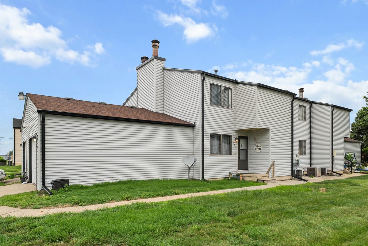 The two-story townhomes from the side, with attached garages and a lawn.