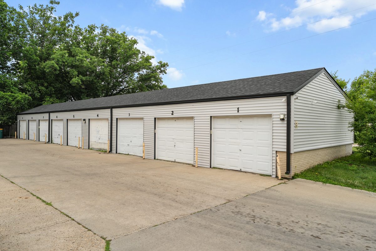 A row of detached garages with white overhead doors along the drive.